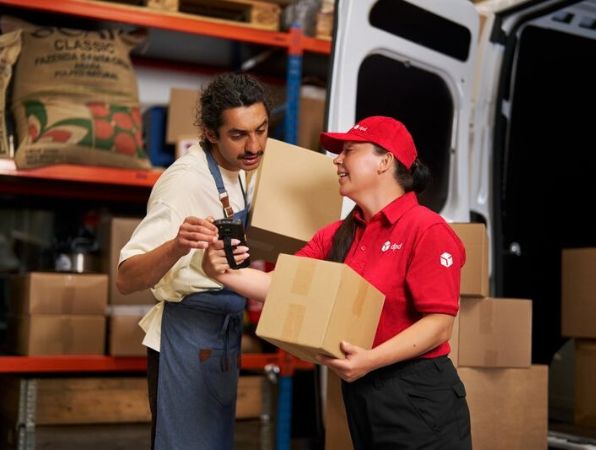 Remise d’un colis entre deux personnes dans un centre logistique.