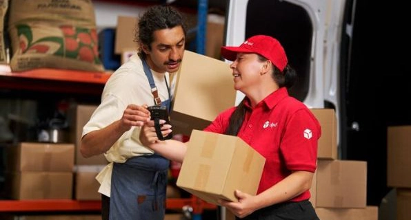 Remise d’un colis entre deux personnes dans un centre logistique.