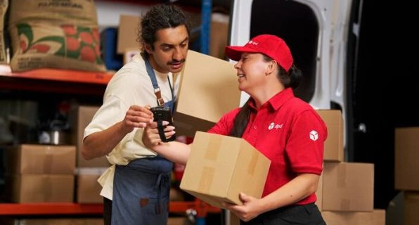 Remise d’un colis entre deux personnes dans un centre logistique.