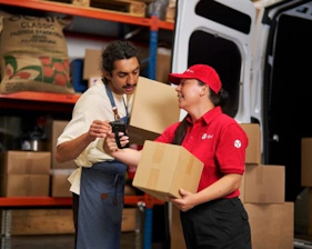 Remise d’un colis entre deux personnes dans un centre logistique.